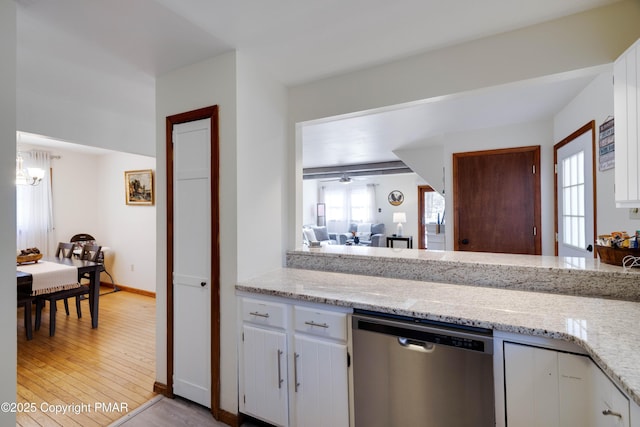 kitchen featuring light stone counters, white cabinets, light wood finished floors, and stainless steel dishwasher