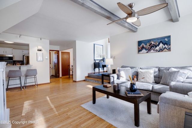 living room featuring beam ceiling, light wood-style floors, a ceiling fan, track lighting, and baseboards