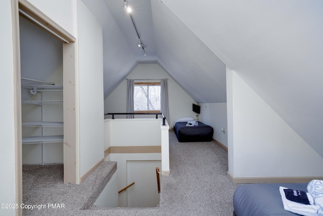 bedroom with lofted ceiling, carpet, baseboards, and track lighting