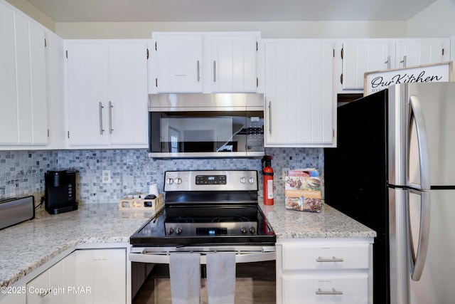 kitchen featuring stainless steel appliances, light stone counters, backsplash, and white cabinets