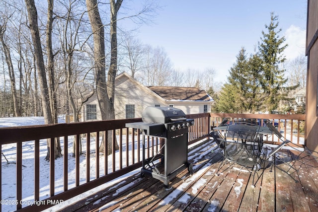 snow covered deck with outdoor dining area and grilling area