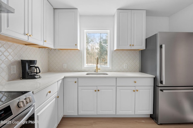 kitchen featuring a sink, stainless steel appliances, light countertops, under cabinet range hood, and white cabinetry