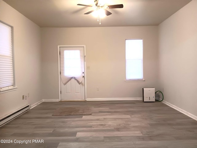 spare room featuring baseboards, a baseboard radiator, a ceiling fan, and wood finished floors