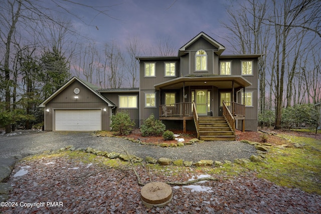 view of front of house with driveway, stairs, a garage, and a porch