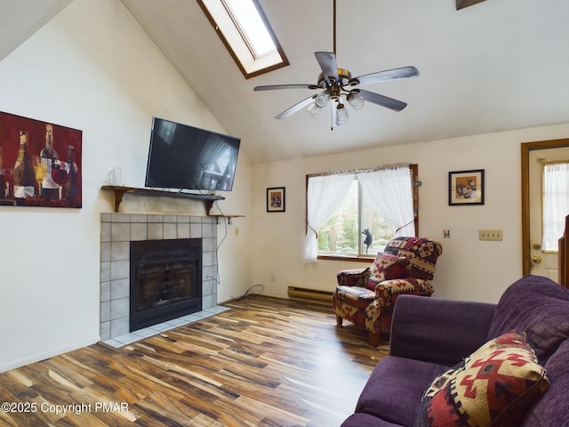 living area with a ceiling fan, a tile fireplace, a skylight, and wood finished floors