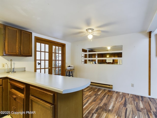 kitchen with dark wood-style floors, a peninsula, light countertops, french doors, and a baseboard heating unit