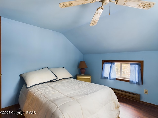 bedroom with a baseboard heating unit, vaulted ceiling, and wood finished floors