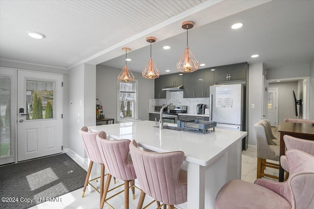 kitchen with light countertops, backsplash, freestanding refrigerator, stainless steel electric stove, and a kitchen bar