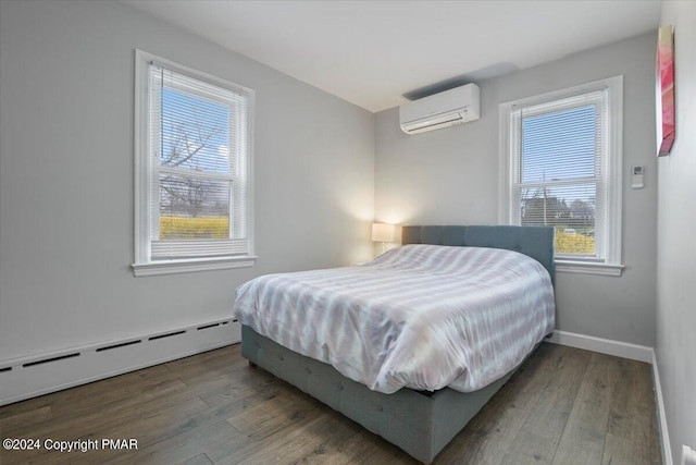 bedroom featuring baseboards, a wall unit AC, baseboard heating, and wood finished floors