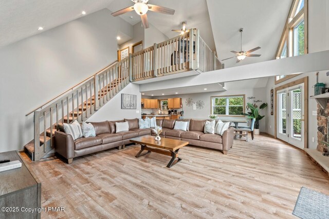 living room featuring high vaulted ceiling, ceiling fan, and light wood-type flooring