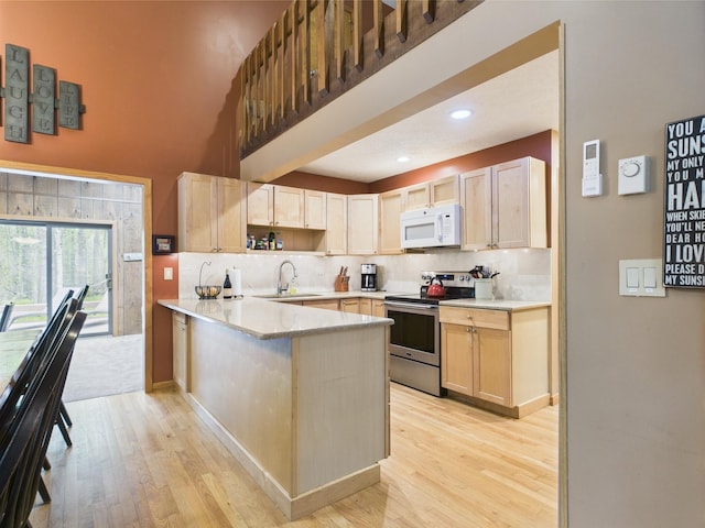 140 Boones Trl, Pocono Pines, PA 18350 - kitchen with white microwave, stainless steel range with electric stovetop, a peninsula, a sink, and light wood finished floors