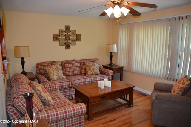 living area with baseboards, wood finished floors, visible vents, and ceiling fan