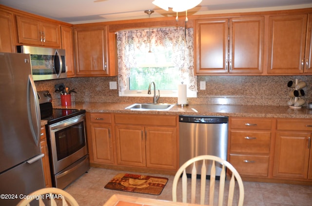 kitchen with backsplash, stainless steel appliances, brown cabinets, and a sink