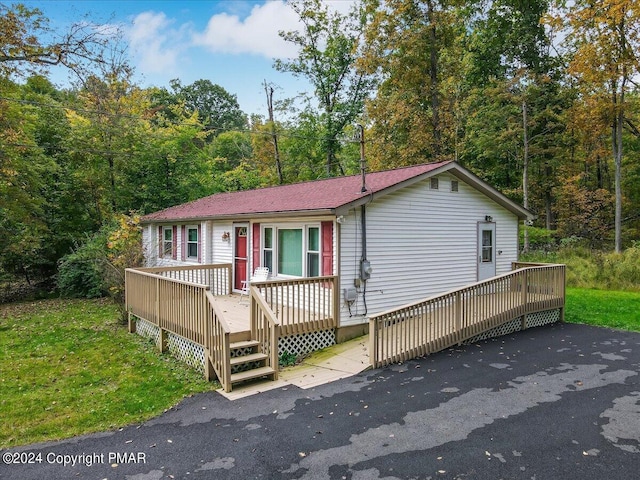 view of front of house featuring a wooden deck and a view of trees