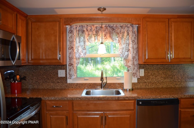 kitchen featuring backsplash, appliances with stainless steel finishes, brown cabinets, and a sink