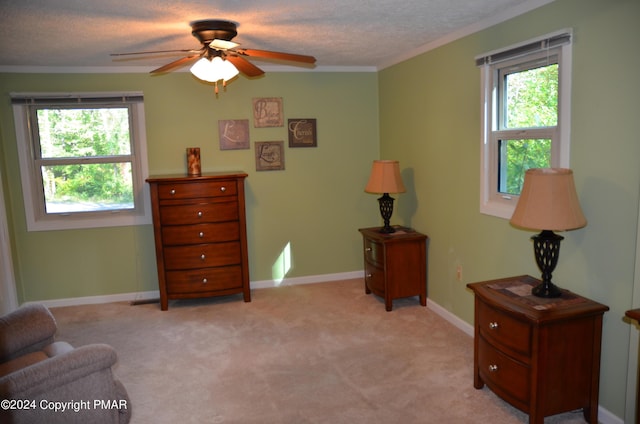 sitting room featuring a wealth of natural light, light colored carpet, crown molding, and ceiling fan