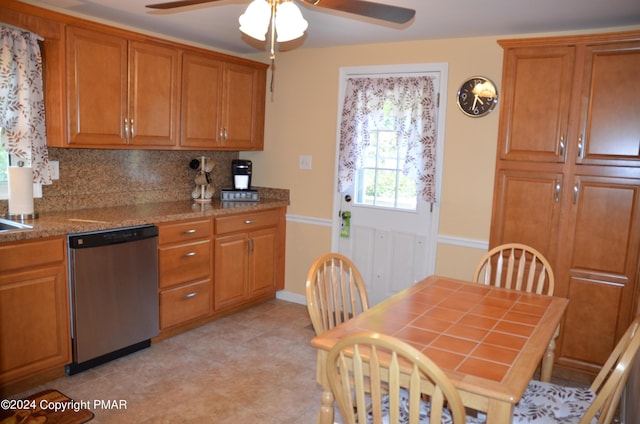 kitchen featuring brown cabinets, stainless steel dishwasher, a ceiling fan, and tasteful backsplash