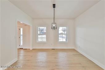 unfurnished dining area featuring light wood-style flooring and baseboards