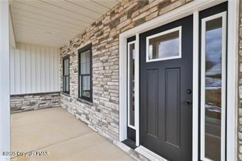 property entrance featuring a porch and brick siding