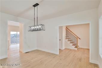 unfurnished dining area featuring stairway, baseboards, and wood finished floors