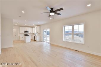 unfurnished living room with light wood-type flooring, baseboards, a ceiling fan, and recessed lighting