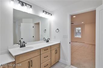 bathroom with double vanity, a sink, and baseboards