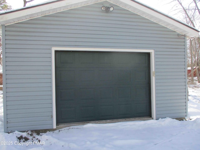 snow covered garage with a detached garage