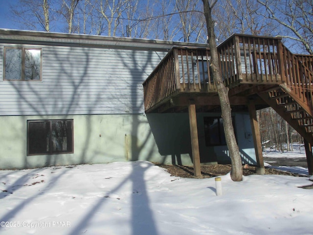 snow covered house featuring stairs and a deck