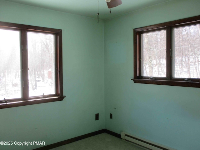 empty room featuring ceiling fan, baseboard heating, plenty of natural light, and baseboards