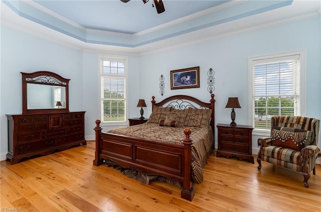 bedroom with light hardwood / wood-style flooring, a raised ceiling, multiple windows, and ceiling fan