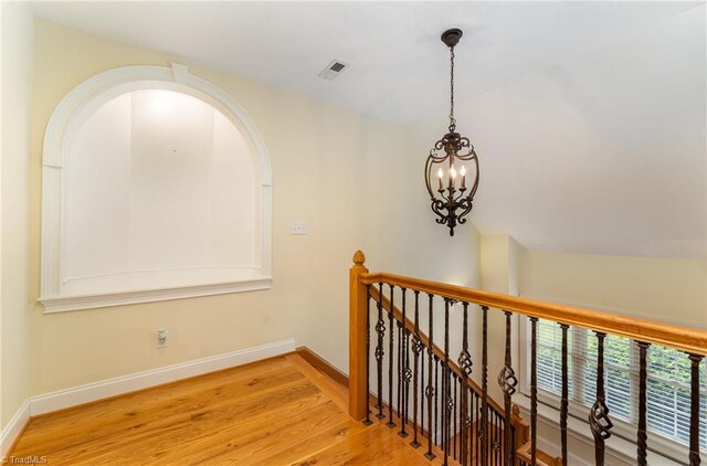 corridor featuring a chandelier, vaulted ceiling, and light hardwood / wood-style floors