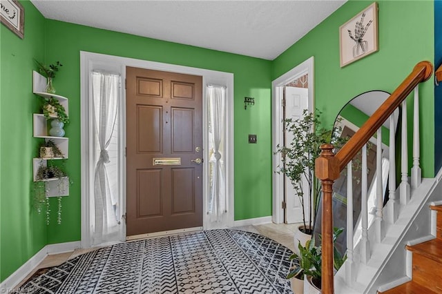 foyer entrance featuring stairs, baseboards, and light tile patterned flooring