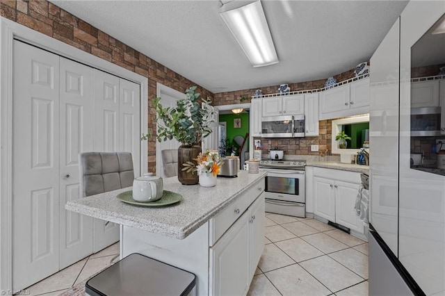 kitchen featuring appliances with stainless steel finishes, a center island, white cabinets, and light tile patterned floors