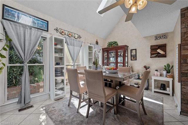 tiled dining space featuring a ceiling fan, visible vents, high vaulted ceiling, and a textured ceiling