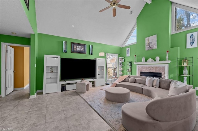 living area featuring baseboards, ceiling fan, tile patterned floors, a fireplace, and high vaulted ceiling