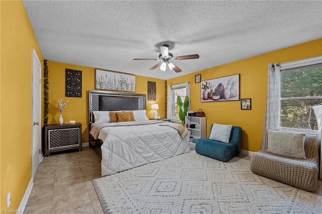 tiled bedroom with a textured ceiling, a ceiling fan, and baseboards