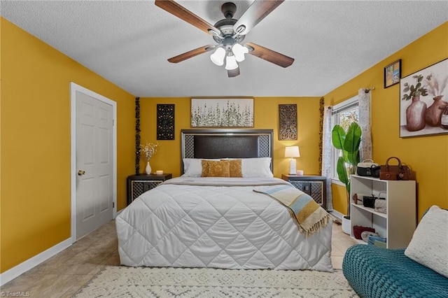 bedroom with tile patterned flooring, baseboards, ceiling fan, and a textured ceiling