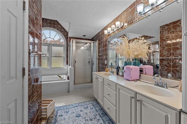 full bathroom featuring tile patterned flooring, a sink, a textured ceiling, and a shower stall