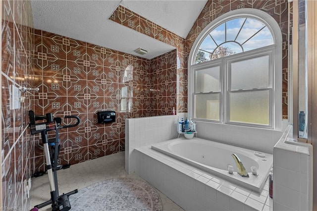 full bath featuring a tub with jets, tile patterned flooring, tile walls, and a healthy amount of sunlight