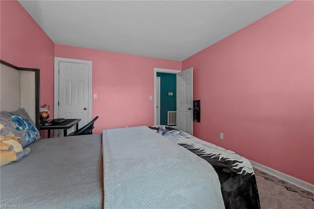 carpeted bedroom featuring visible vents, a textured ceiling, and baseboards