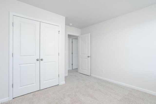 unfurnished bedroom featuring light carpet and a closet