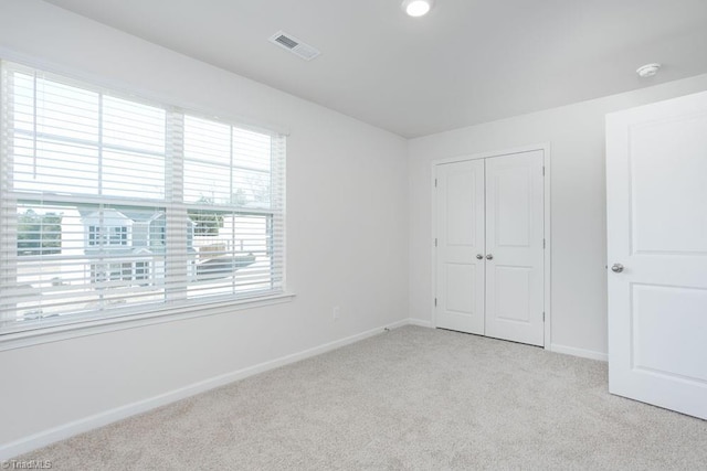 unfurnished bedroom with light colored carpet and a closet