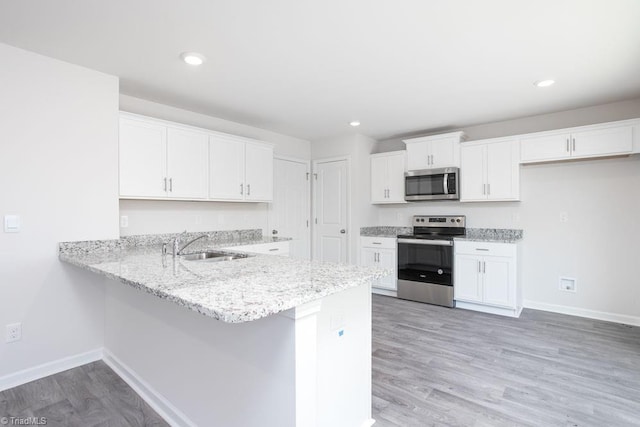 kitchen featuring hardwood / wood-style flooring, appliances with stainless steel finishes, kitchen peninsula, and white cabinets