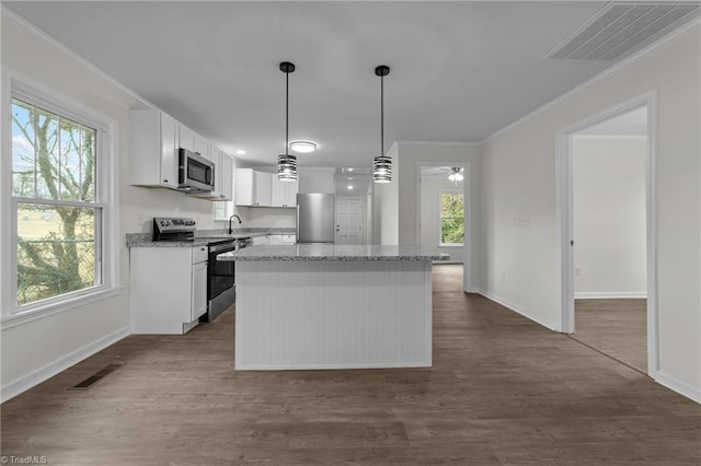 kitchen featuring pendant lighting, crown molding, appliances with stainless steel finishes, white cabinetry, and a kitchen island