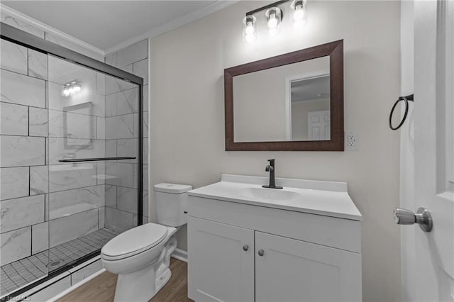 bathroom featuring hardwood / wood-style flooring, crown molding, vanity, toilet, and walk in shower