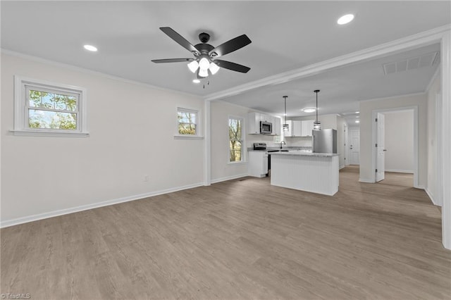 kitchen featuring pendant lighting, white cabinetry, stainless steel appliances, a center island, and ornamental molding