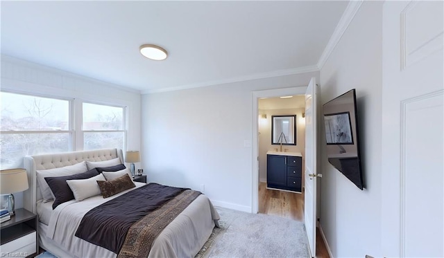 bedroom featuring sink, light wood-type flooring, ornamental molding, and ensuite bathroom