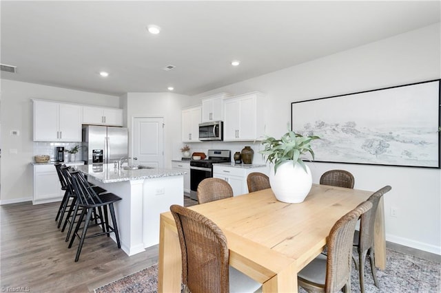 dining space with light wood finished floors, recessed lighting, and baseboards