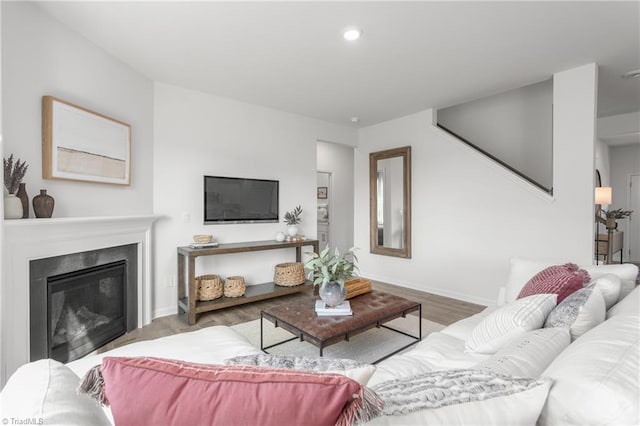 living room with wood finished floors, baseboards, recessed lighting, and a glass covered fireplace