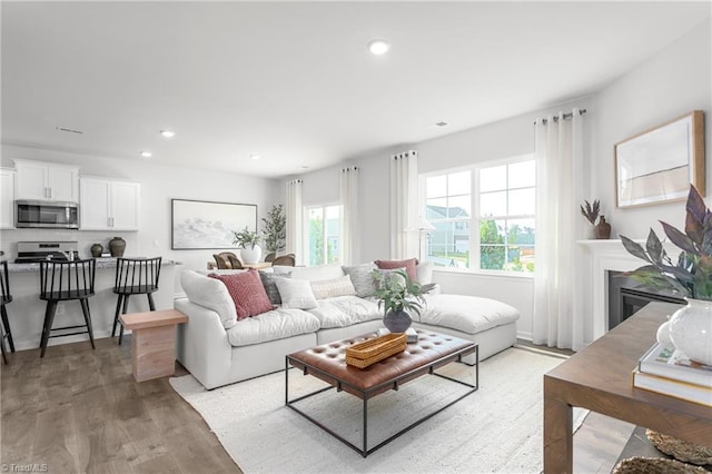 living area with light wood-type flooring, recessed lighting, and a glass covered fireplace